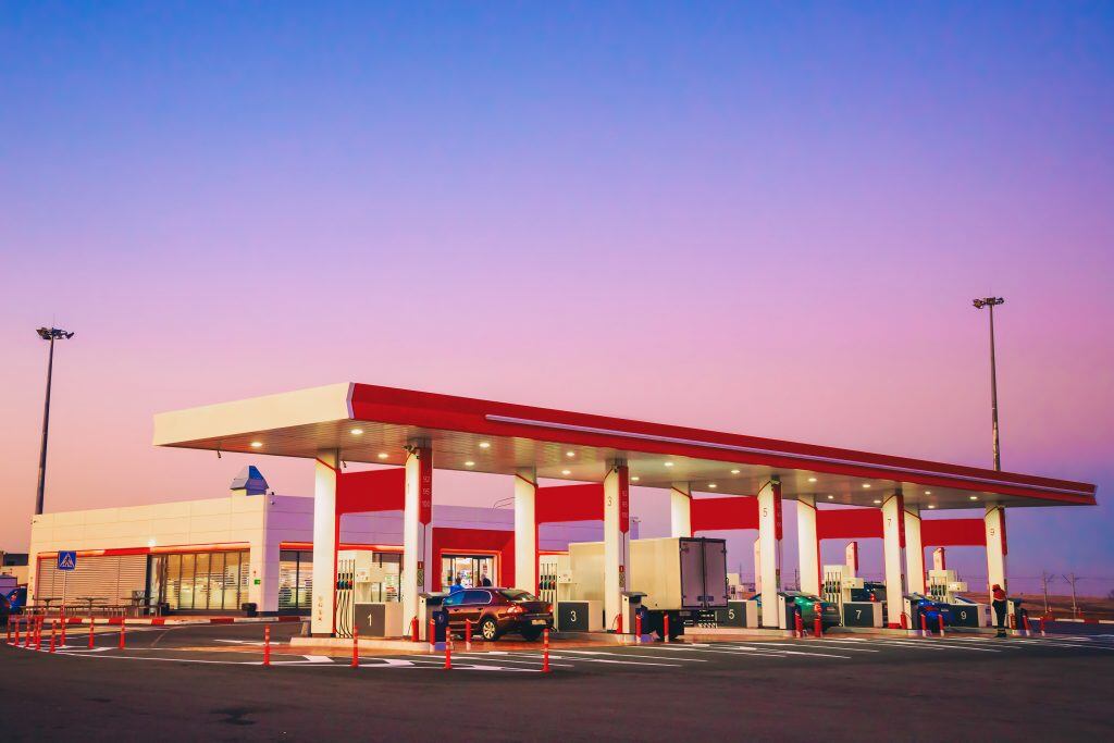 View of a modern automobile gas station with cars standing on the background of a beautiful sunset or dawn
